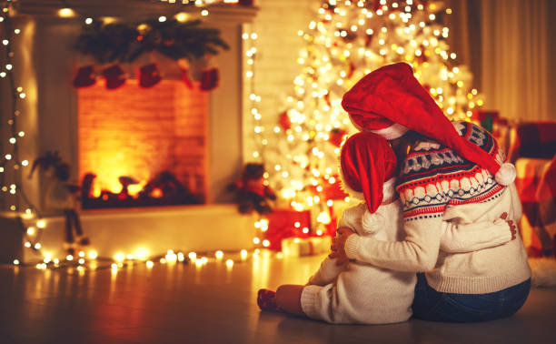 glückliche familie mutter und tochter sitzen rücken in der nähe von baum zu weihnachten - christmas family child christmas tree stock-fotos und bilder