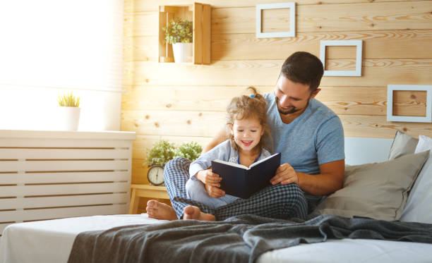 père de famille heureux et livre de lecture fille dans son lit - 7010 photos et images de collection