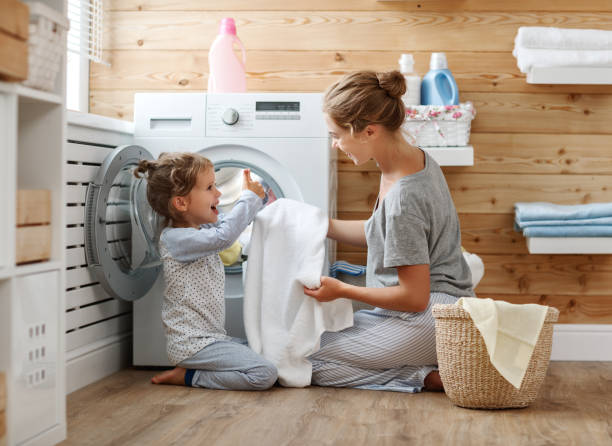 ama de casa feliz madre de familia y el niño en la lavandería con lavadora - stereotypical housewife little girls family domestic kitchen fotografías e imágenes de stock