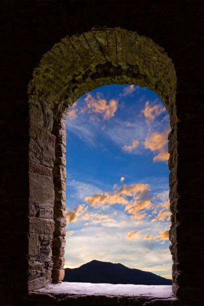 istock Evening sky with blue and red clouds visible through old ancient stone window. 868231196