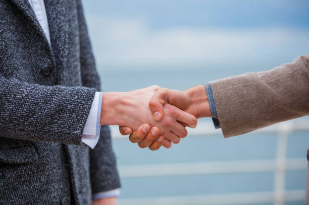 Handsome young boys walking on the street together. Attractive men shaking hands. River on the blurred background. Close-up of men.