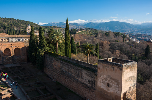 View of courtyard, walls and tower of Alcazaba, citadel of Alhambra, Nasrid with Sierra Nevada mountains in snow at the background . Granada, Spain.