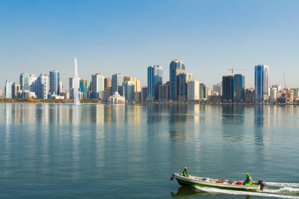 Al Khalid Lake, Sharjah, UAE Boat with city workes crossing Khalid Lake, with the Noor mosque and Water jet in the background sharjah city stock pictures, royalty-free photos & images