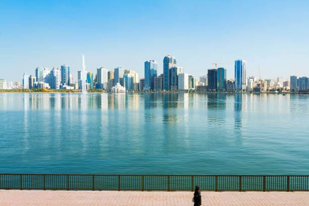 Al Khalid Lake, Sharjah, UAE Woman wearing niqab walking in front Khalid Lake, with Noor mosque and Water jet in the background sharjah city stock pictures, royalty-free photos & images