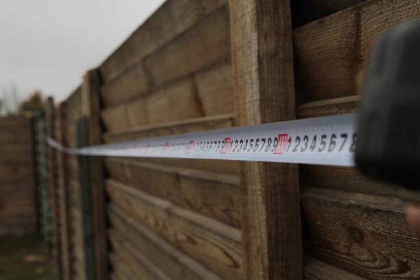 misurazione di una recinzione con un metro a nastro da costruzione nell'area suburbana - house construction tape measure blueprint foto e immagini stock