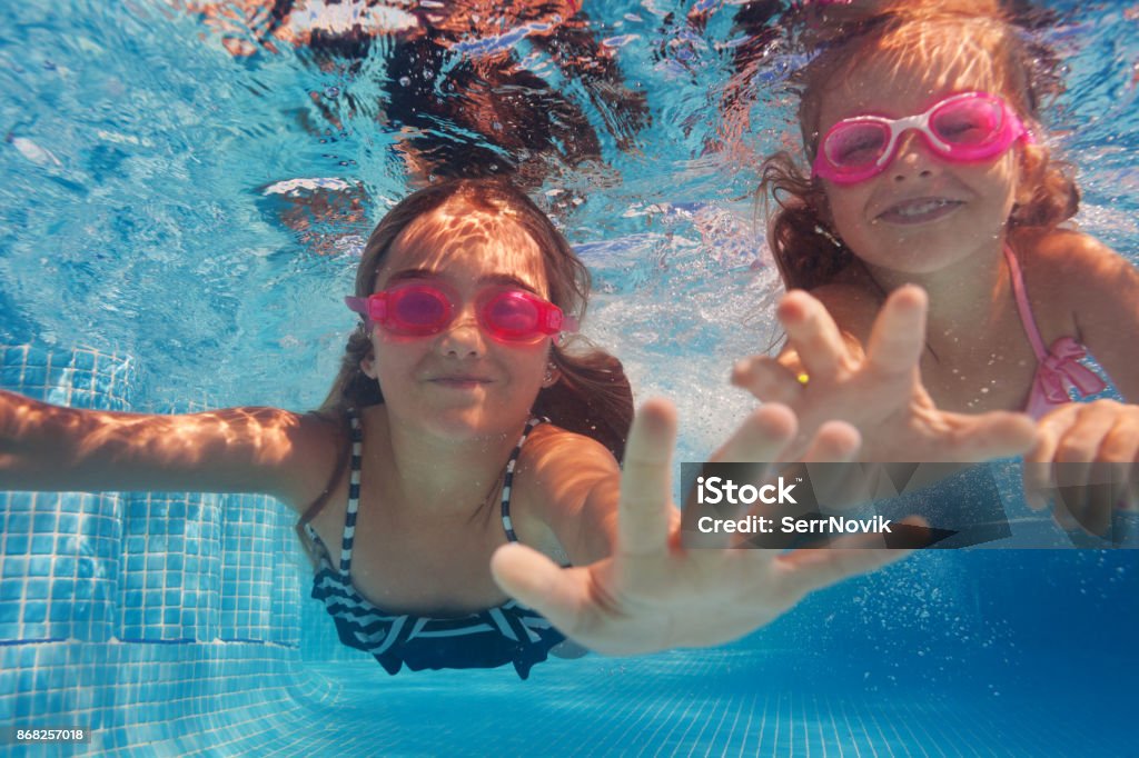 Due ragazze felici in occhiali che nuotano sott'acqua - Foto stock royalty-free di Bambino