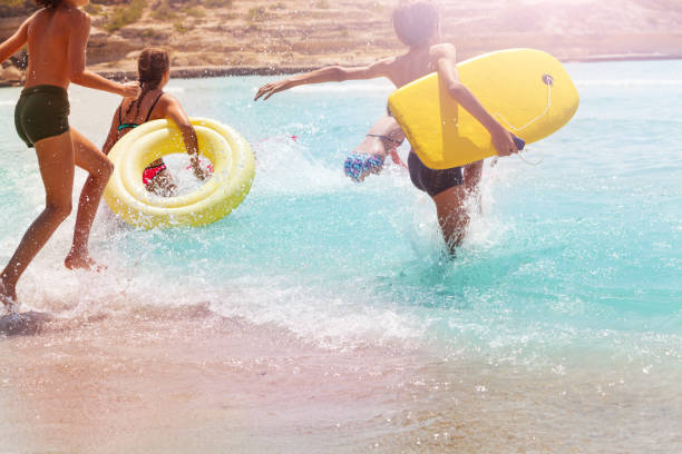 istock Kids run and jump into the water on sand beach 868268050