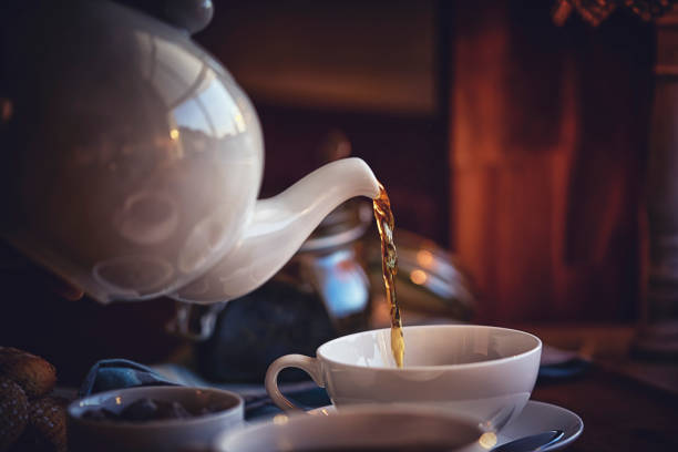 verser le thé noir en coupe - tea cup afternoon tea tea teapot photos et images de collection