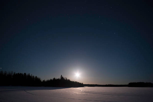 Moon rising over winter landscape at night