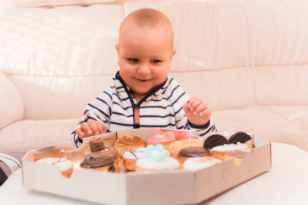 Baby boy smile when he see donuts on the table stock photo