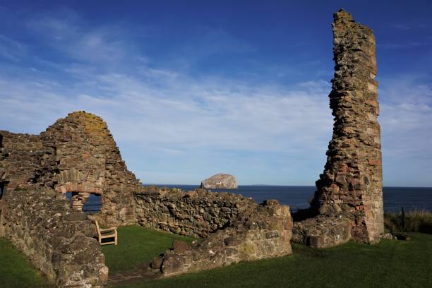 Tantallon Castle ruins and Bass Rock North Berwick, East Lothian, Scotland - October 27, 2017: View looking past the ruins surrounding the old Inner Court of Tantallon Castle looking towards the Bass Rock sitting on the water of the Firth of Forth. A small section of the outer wall forms a narrow pillar. The Bass Rock is formed from a volcanic plug resulting in a small island where the Firth of Forth merges into the North Sea. north berwick scotland east lothian castle scotland stock pictures, royalty-free photos & images