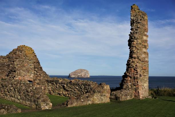 Tantallon Castle ruins and Bass Rock North Berwick, East Lothian, Scotland - October 27, 2017: View looking past the ruins surrounding the old Inner Court of Tantallon Castle looking towards the Bass Rock sitting on the water of the Firth of Forth. A small section of the outer wall forms a narrow pillar. The Bass Rock is formed from a volcanic plug resulting in a small island where the Firth of Forth merges into the North Sea. north berwick scotland east lothian castle scotland stock pictures, royalty-free photos & images
