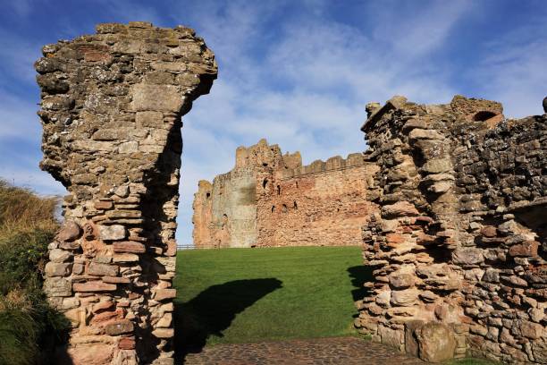 Tantallon Castle through outer entrance North Berwick, East Lothian, Scotland - October 27, 2017: View of the red sandstone wall forming the frontage of Tantallon castle, looking through the remains of the entrance of the outer protective wall. north berwick scotland east lothian castle scotland stock pictures, royalty-free photos & images