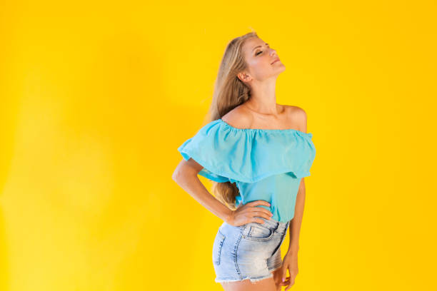 beautiful blonde with blue shorts on a yellow background