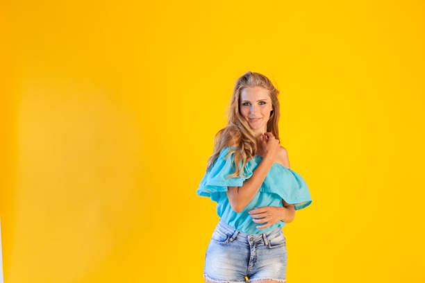 istock beautiful blonde with blue shorts on a yellow background 868288740