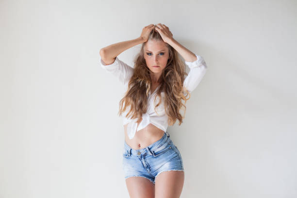 girl in blue shorts blonde posing against a wall 1