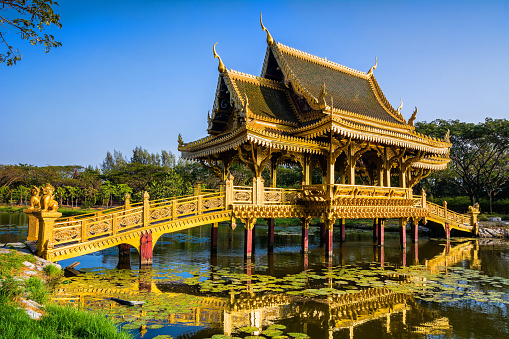 Amazing view of beautiful Golden Bridge and Pavilion of the Enlightened with reflection in the water. Location: Ancient City Park, Muang Boran, Samut Prakan province,  Bangkok, Thailand. Artistic picture. Beauty world.