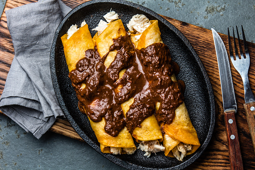 Mexican cuisine. Traditional Mexican chicken enchiladas with spicy chocolate salsa mole poblano. Enchiladas with sauce moole from Puebla, Mexico.