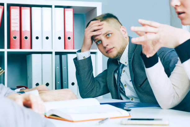 istock Pensive young handsome man looking on his colleague while sitting at the office table on business meeting. 868325304