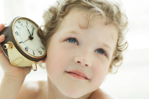 istock Dreamy little boy listen an antique clock. 868325328