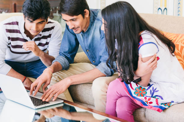 istock Group of indian millennials looking at a laptop and talking about business, homework or project together. 868325512