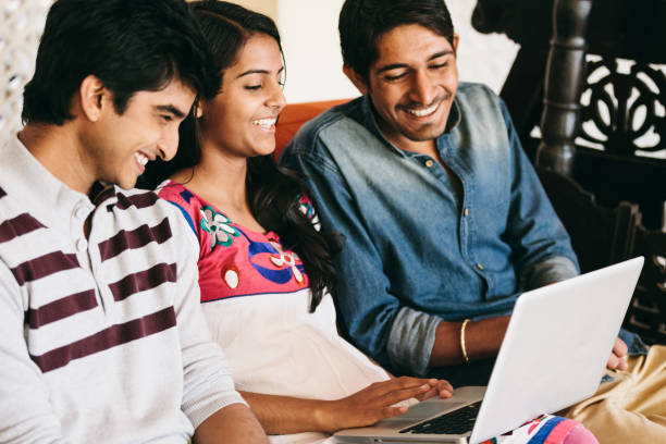 istock Group of indian millennials looking at a laptop and talking about business, homework or project together. 868325652