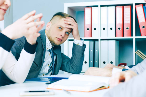 istock Pensive young handsome man looking on his colleague while sitting at the office table on business meeting. 868335674