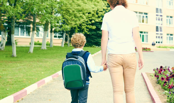 お母さんのアウトドアのバックパックを幼い息子の手を握って、学校に戻る。教育、子供のころや家族の概念。 - little boys preschooler back to school backpack ストックフォトと画像