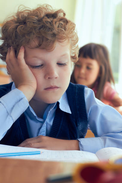 istock Schoolboy reading book at his desk in elementary school lesson. 868335748