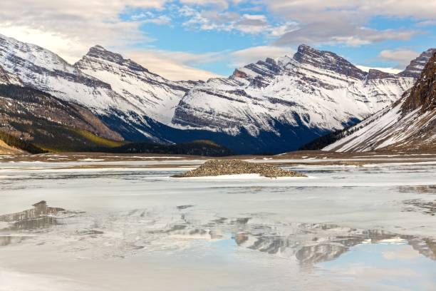 Global Warming Effects in Canadian Rocky Mountains Distant Snowcapped Mountains reflected in meltwater below Saskatchewan Glacier in Columbia Icefields between Banff and Jasper National Parks, Alberta, Canada saskatchewan glacier stock pictures, royalty-free photos & images