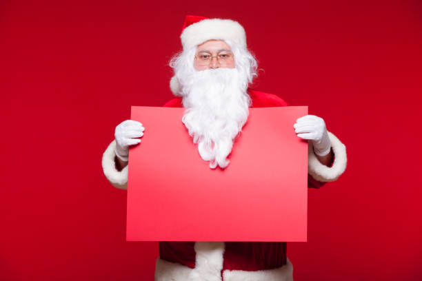 istock Santa Claus pointing in blank advertisement banner isolated on red background with copy space red leaf 868362908