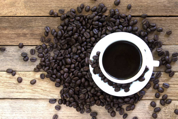 istock Coffee beans and black coffee cup on wood background. Top view with copy space for your text 868366528