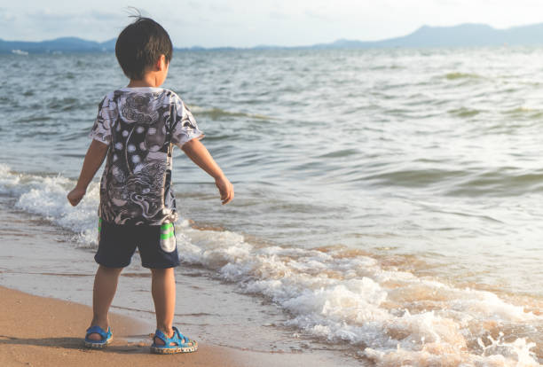 istock Little Asian boy is standing by the Beach 868373736