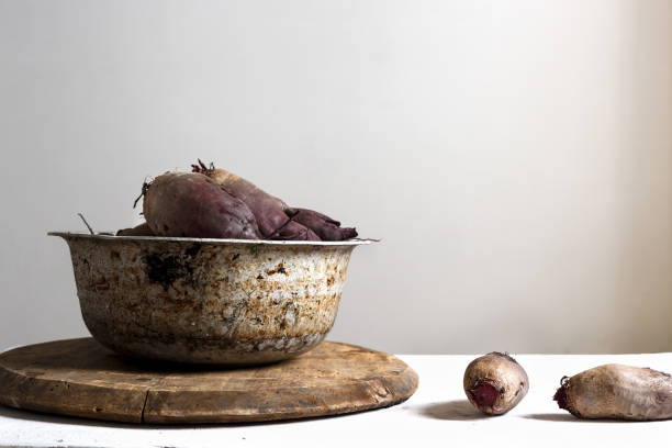 Fresh beet in old metal ware, costs on a table, on a light background. Copy space