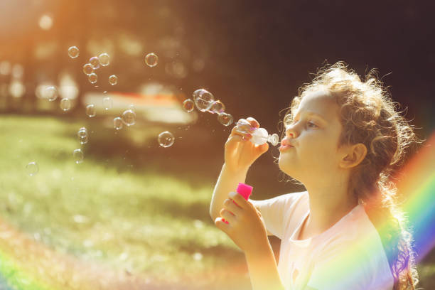 istock Little girl blowing soap bubbles in autumn park. 868373896