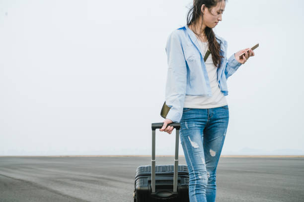 istock young woman walking with suitcase using phone 868373988