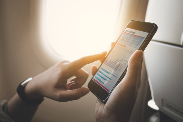 imprenditrice su aereo con smartphone con grafico sullo schermo - airplane smart phone travel mobile phone foto e immagini stock
