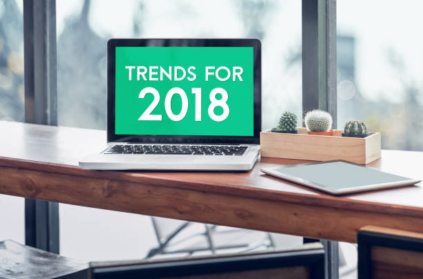 istock Trends for 2018 word in laptop computer screen with tablet on wood stood table in at window with blur background,Digital Business or marketing trending 868377350