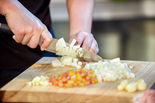 istock Closeup hand chef cutting up an onion with a knife on board 868381266