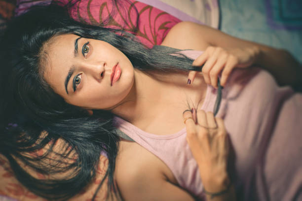 teenage girl with long red hair is relaxing in chair with her bare feet up looking at the camera.