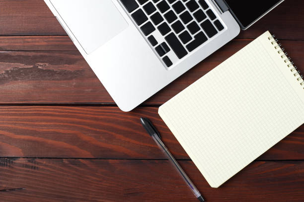 istock Laptop with notepad and pen on wooden desk. 868389584