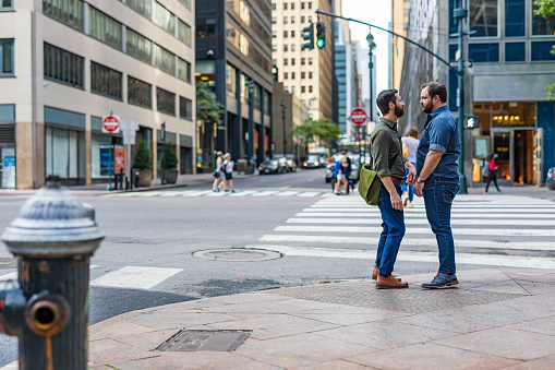 Mature adult gay men walking outdoors though New York while holding hands