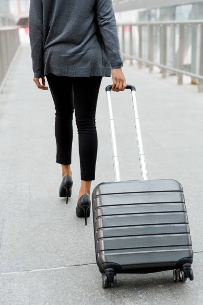 istock Unrecognizable businesswoman pulling suitcase inside of airport terminal 868395396