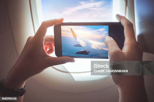 Female Taking A Photo With Smartphone On Plane Stock Photo - Download Image Now - Airplane, Telephone, Women