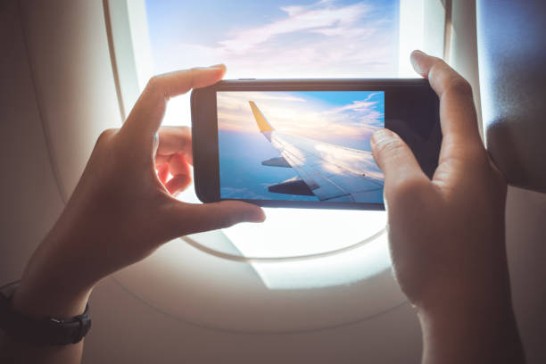 женщина, сфотографироваться со смартфоном в самолете. - air travel фотографии стоковые фото и изображения