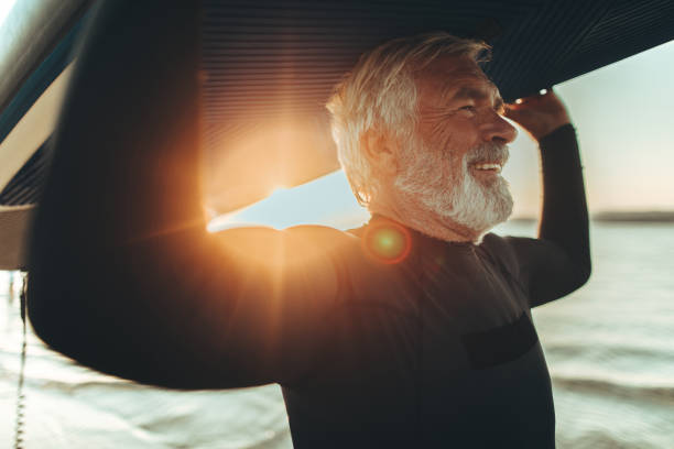 Senior surfer Photo of a senior man who still enjoys surfing and summer activities paddleboard photos stock pictures, royalty-free photos & images