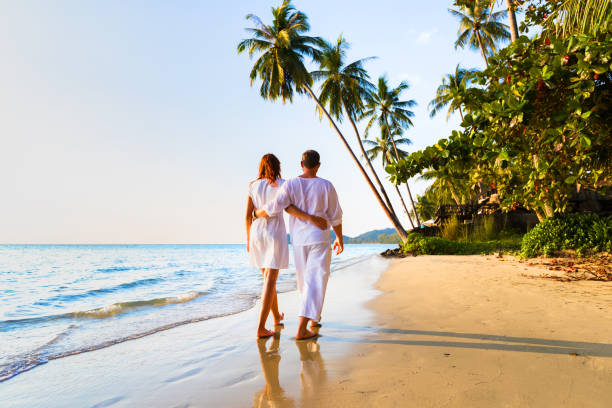 istock Romantic couple walking together on tropical beach, sunny summer honeymoon 868399792