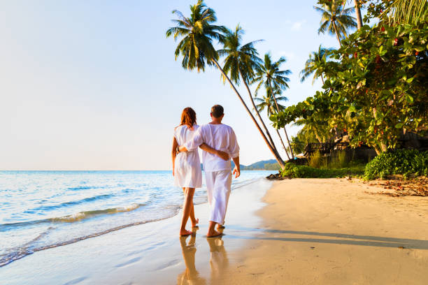 Romantic couple walking together on tropical beach, sunny summer honeymoon Romantic couple walking together on the tropical beach in warm sunny summer during honeymoon vacations honeymoon beach stock pictures, royalty-free photos & images