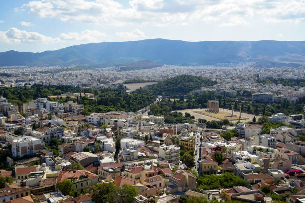 istock Panoramic view of Athens city from Acropolis seeing ancient ruin, building architecture, urban street, trees, mountain and bright sky background 868399990
