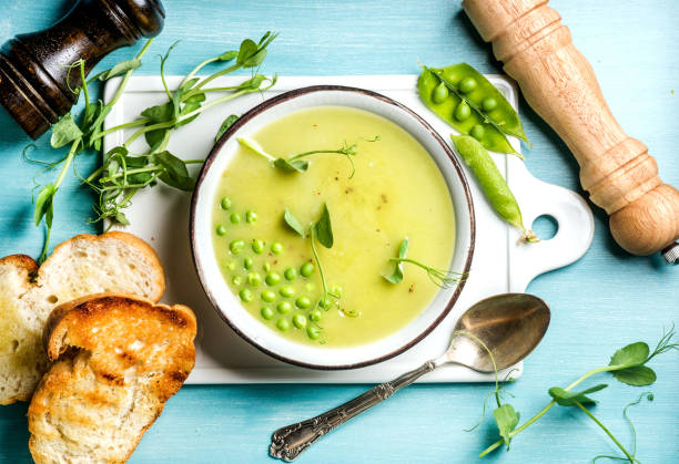 zuppa di crema di piselli verde estate leggera in ciotola con germogli, toast al pane e spezie - light meal foto e immagini stock